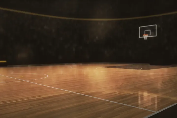A lit basketball arena floor seen from the baseline